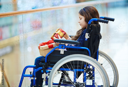 Fotografia, Obraz Side-view of disabled child in wheelchair looking at gift-box