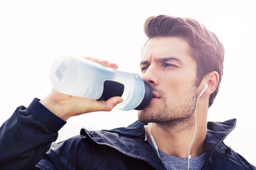 Wall Mural - Handsome man in headphones drinking water