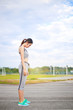 © noombluesman - Young woman wearing sports clothes standing on the track at the stadium.