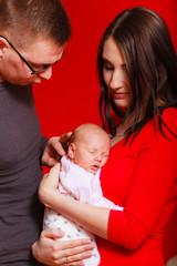 Newborn on mother chest father next to them