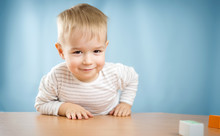 Portrait Of A Two Years Old Child Sitting At The Table
