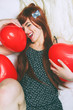 Chica joven y pelirroja abrazando globos rojos con forma de corazón 