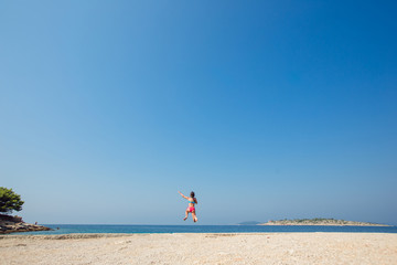 Wall Mural - Child little girl is jumping into the sea from a pier