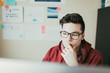 © ZeroThree - Man wearing glasses working on a computer