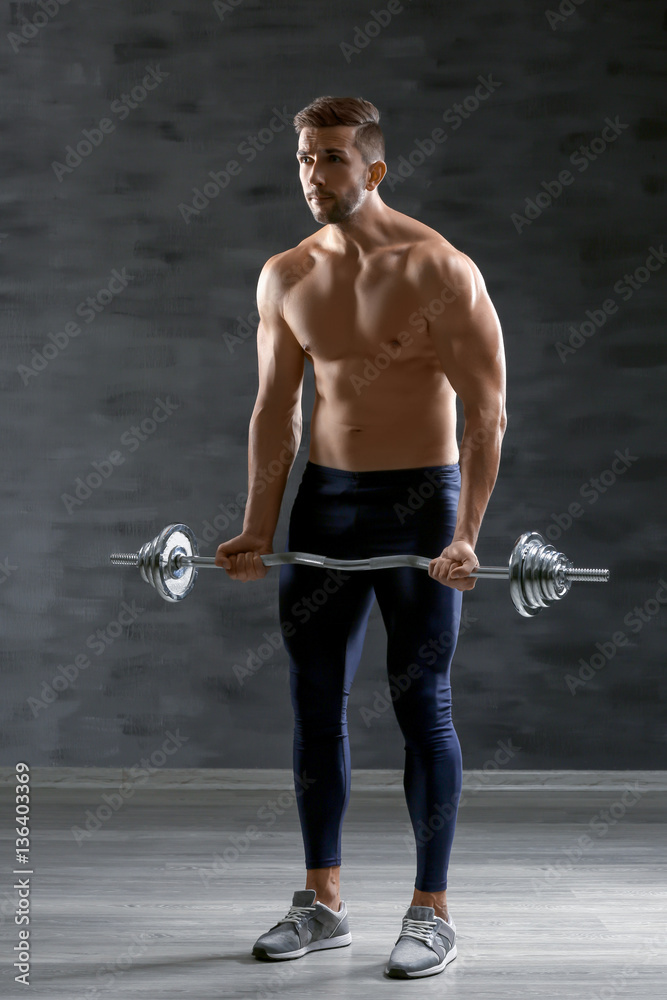 Sporty man doing exercises with barbell indoors
