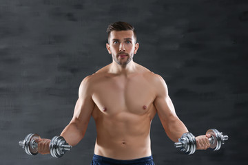 Wall Mural - Sporty man doing exercises with dumbbells on dark background