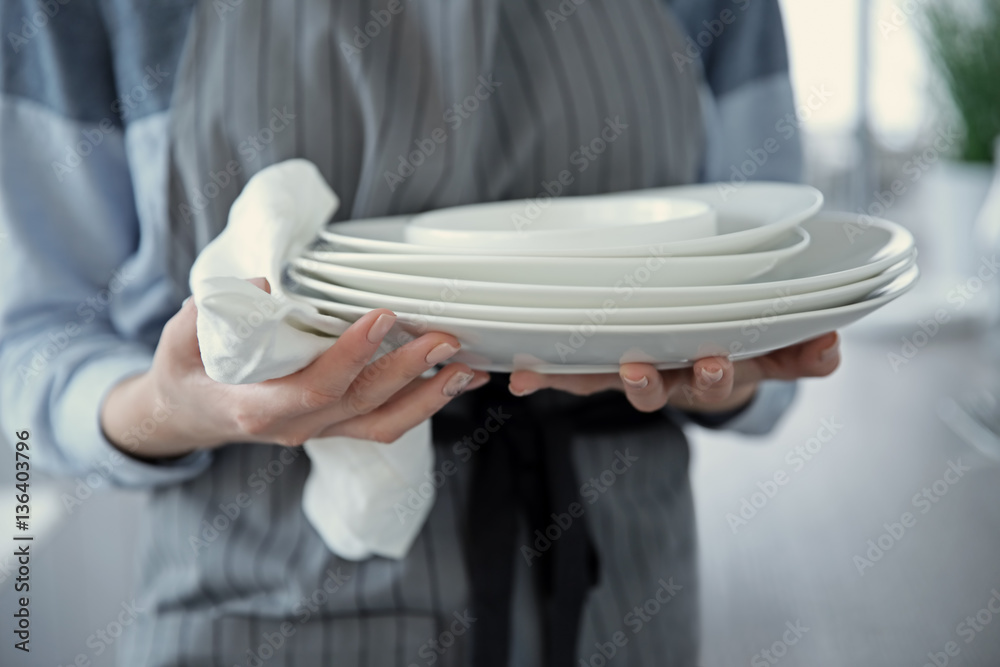 Woman in apron holding dishes, closeup