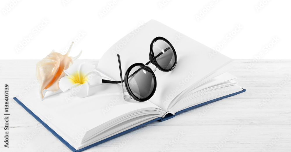 Vacation concept. Sunglasses, flower and shell on opened book