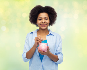 Poster - happy african woman putting coin into piggy bank