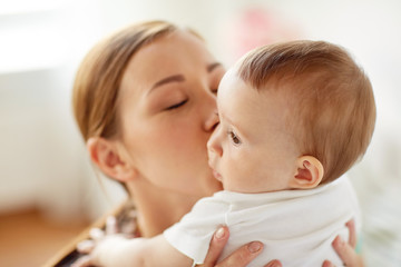 Wall Mural - happy young mother kissing little baby at home