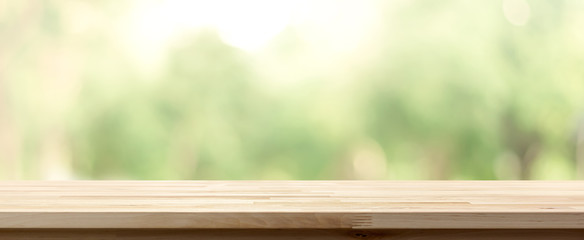 Wood table top on blur green background of trees in the park
