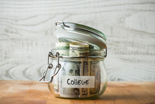 Dollar Bills In Glass Jar Isolated On Wooden Background. Saving Money For College.. 
