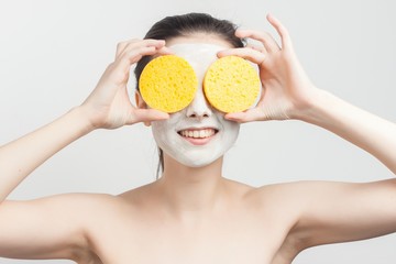 smiling woman with mask on face holds near eyes two sponge