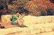 © R - Couple man and woman sitting on wooden boards near a stone wall