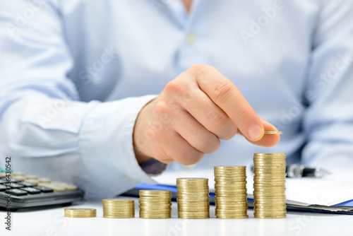 Fotografía Male hand putting money coin stack growing business, saving money concept