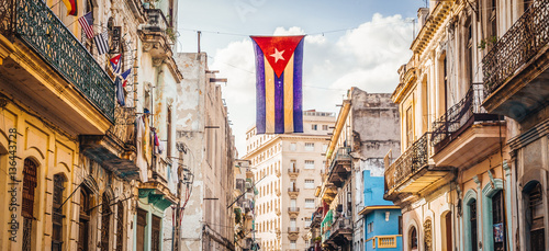 A cuban flag with holes waves over a street in Central Havana Wallpaper Mural