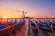 Gondolas moored to the poles in Europe Venice near the city center and Saint Mark square with a background view of the church of San Giorgio Maggiore at sunrise soft light