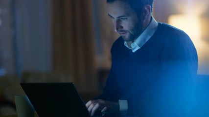 Aufkleber - Middle Aged Man Sitting at His Desk Working on a Laptop. In the Background His Apartment in Yellow Tones with a Skyscrapers View. Shot on RED EPIC-W 8K Helium Cinema Camera.