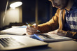 © Cavan Images - Man studying while sitting in library at night