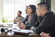 © Cavan Images - Smiling students sitting at table during lesson in classroom