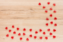 Valentines Background, Border Out Of Small Shiny Red Acrylic Hearts On Light Brown Wooden Background With Lots Of Copy Space. 
