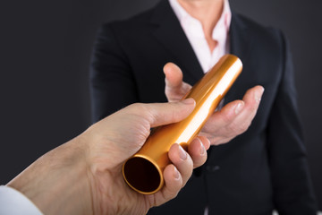 Businessman Passing A Golden Relay Baton