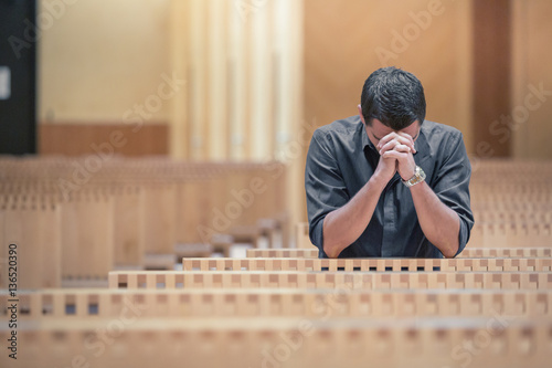 Fotografie, Obraz Young beard man wearing blue shirt praying in modern church