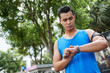 © DragonImages - Portrait of modern young sportsman in blue T-shirt using gadgets during training in summer park