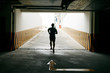 © DragonImages - Back view of young sportsman in shorts and T-shirt running out of underground parking lot, full-length portrait