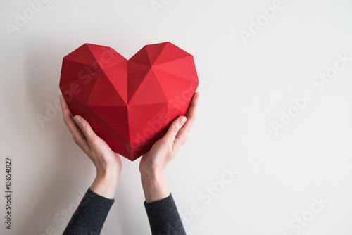 Cuadros en Lienzo Two female hands holding red polygonal paper heart shape