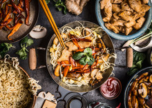 Asian Kitchen Table With Food Bowls, Wok , Stir Fry , Chopsticks And Ingredients On Background, Top View