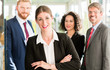 © Kzenon - Businesswoman with crossed arms and her team standing in the bac