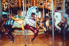 Old French Carousel In A Holiday Park. Three Horses And Airplane On A Traditional Fairground Vintage Carousel. Merry-go-round With Horses.