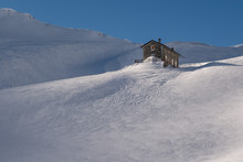 Alpine Refuge Below Mountain Ridge In Winter On Windswept Snow U