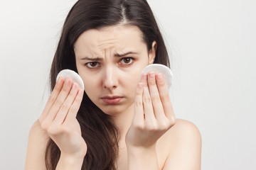 a woman with a sullen face holds two wadded disks