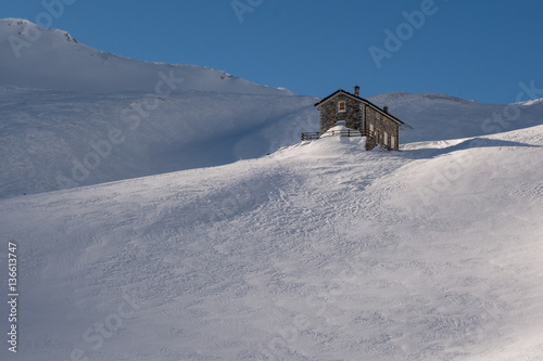 Alpine Refuge Below Mountain Ridge In Winter On Windswept Snow U Alpine Refuge Below Mountain Ridge In Winter On Windswept Snow U