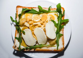 Sandwich with two kinds of cheese and mushrooms and arugula for breakfast