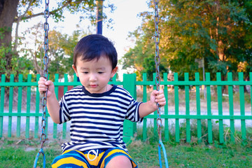 Wall Mural - Young Asian boy play a iron swinging at the playground under the