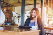© sutadimages - Woman using smart phone in a cafe,image of young woman sitting at a table with a coffee using mobile phone.