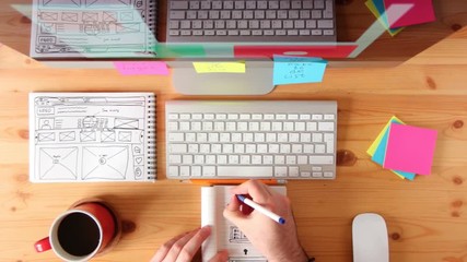 Top view of working place. Webmaster draws the future layout of the web pages in the sketch book.