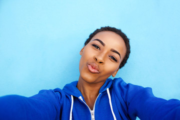 Wall Mural - Portrait of attractive young black woman kissing when taking selfie