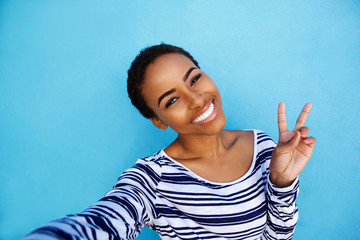 cool young black woman taking selfie with peace hand sign