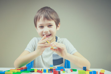 Wall Mural - Smiling little kid playing with colorful plastic construction bricks at home