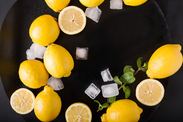 Lemons, mint, ice on a black background. Healthy food concept. Copyspace