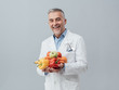 © stokkete - Smiling nutritionist holding fresh vegetables and fruit