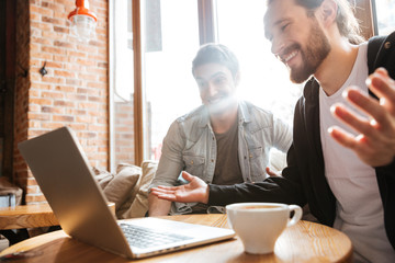 Side view of Surprised Smiling Friends with laptop in cafe