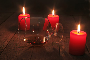 glass of wine or cognac and red candle on a wooden background.