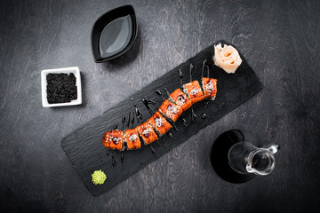 Wall Mural - Tasty and delicious traditional japanese sushi roll with seafood and fish on black wooden background