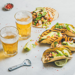 Wall Mural - Healthy corn tortillas with grilled chicken fillet, avocado, fresh salsa, limes, beer in glasses over light grey marble background, selective focus, square crop. Gluten-free, weight loss concept