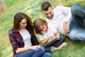 Wall Mural - Happy family in a urban park playing with tablet computer